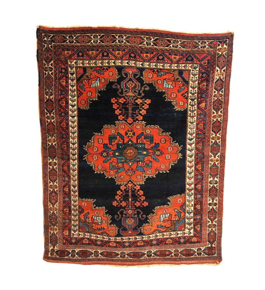 An antique Persian Afshar rug with a vibrant floral-patterned design in shades of red, blue, green, and beige, featuring a dark indigo field and decorative vases at the top and bottom.
